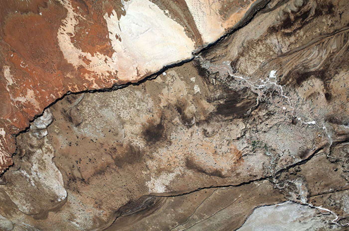 Abb. 6: Ehemaliger Küstenstreifen, der durch den Rückgang des Wassers entstanden ist. Jeder Streifen entspricht dem Meeresspiegelrückgang eines Jahres. Er kann bis zu 50 m breit sein. Im Schlamm und in den Salzablagerungen sind Fußspuren zu erkennen. 