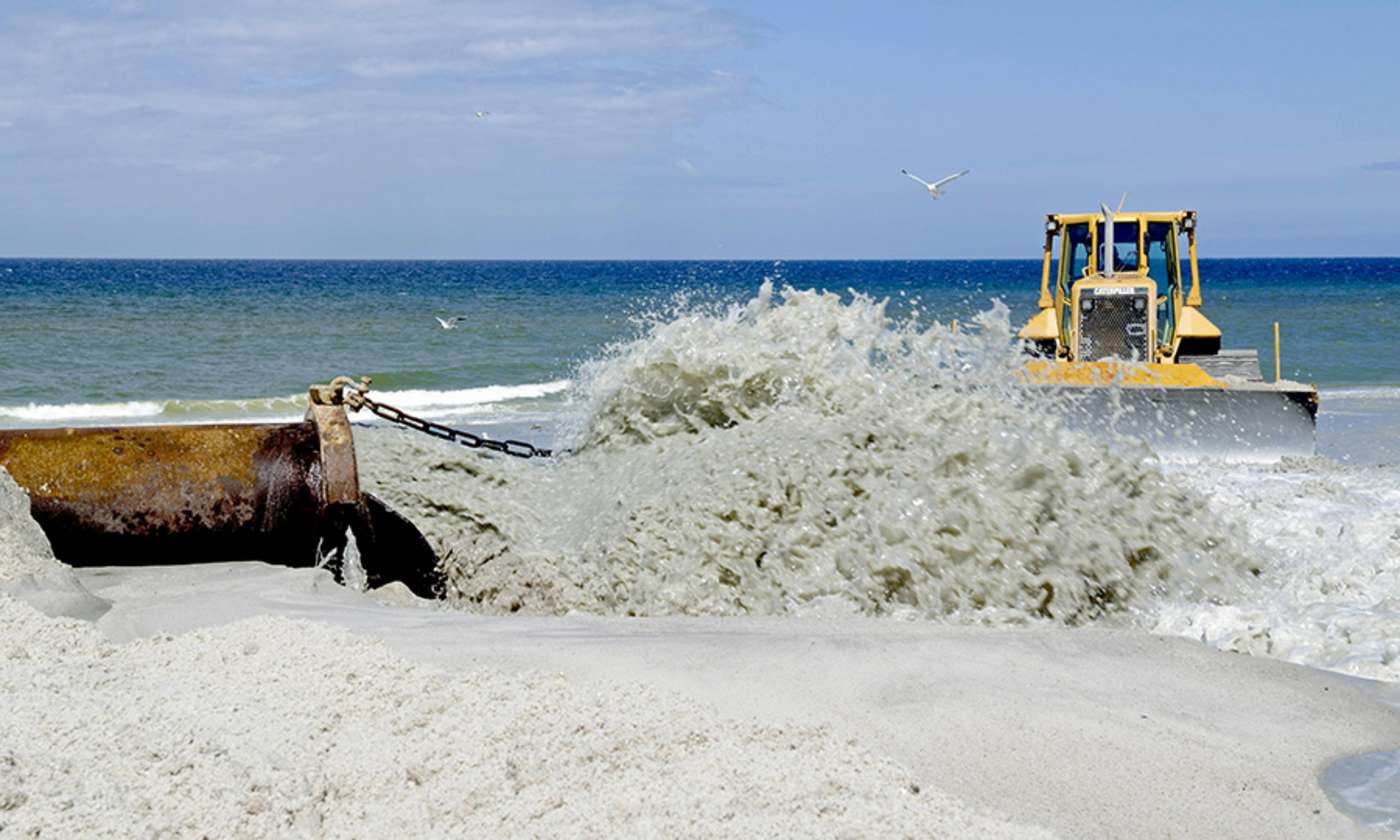 Wasser-Sandgemisch sprudelt aus Rohr auf Strand