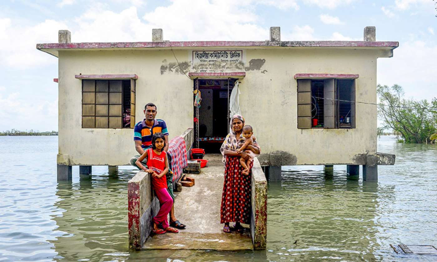 Familie steht vor Haus im Wasser